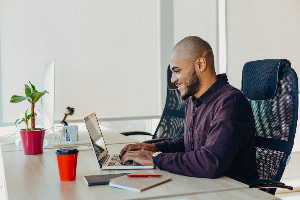 Person smiling whilst typing on laptop