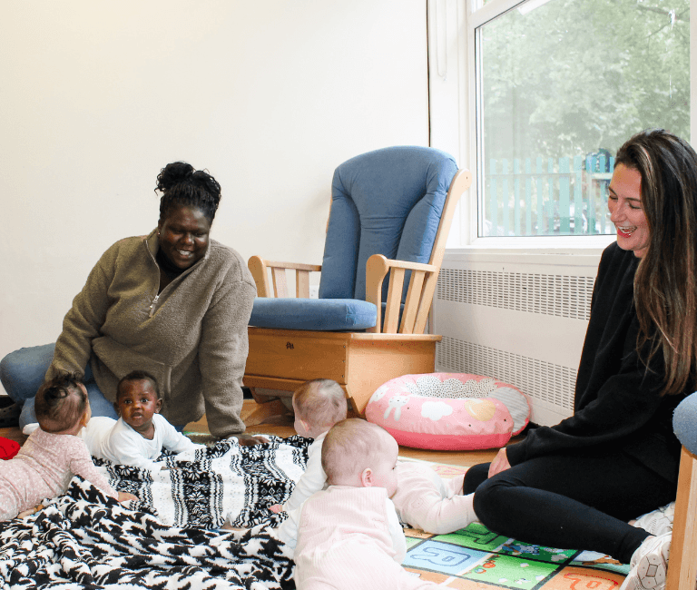 Two mums looking at their baby's playing on the floor
